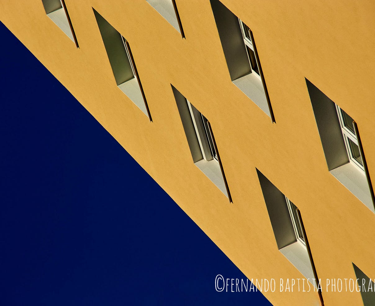 Schräge Hausfassade vor tiefblauen Himmel.