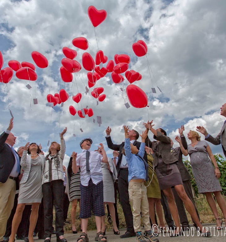 Hochzeitsgesellschaft lässt Herz-Luftballons in den Himmel steigen.